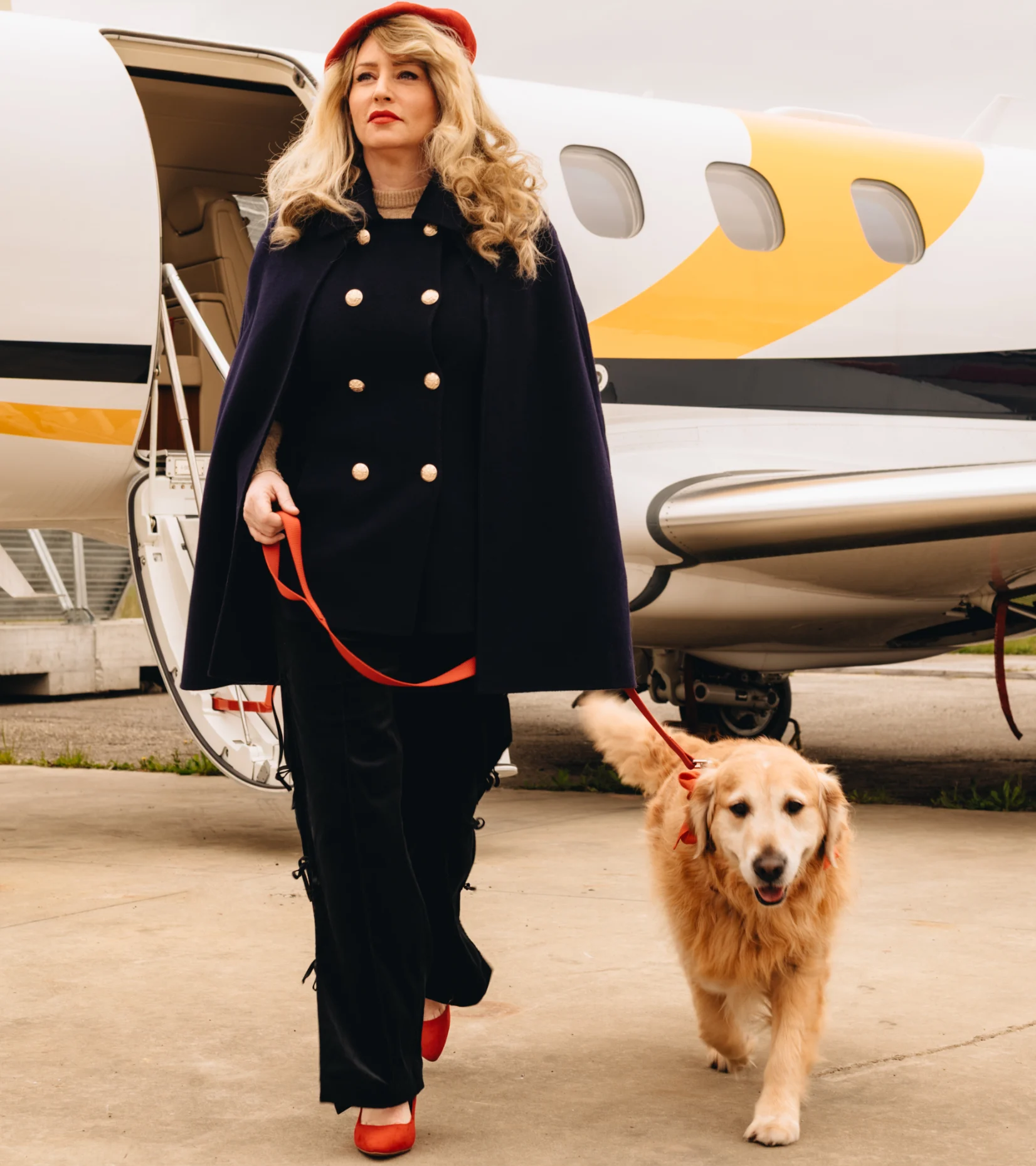 partnership-of-passion-and-expertise Stylish traveller steps away from a small private jet while walking a golden retriever on a lead