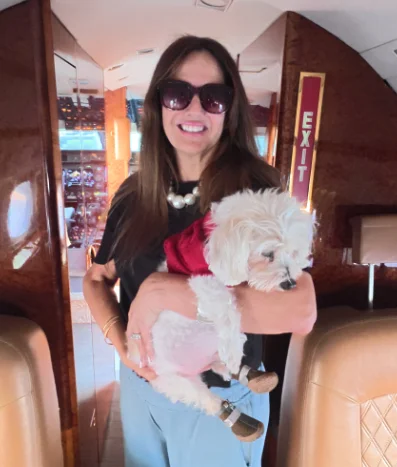 Person holding a small dog inside a private jet